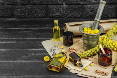 Verbascum çiçekleriyle doğal cilt bakımı, yağlar, kremler ve güzellik tedavileri için bitkisel malzeme. Siyah tahta arkaplan, boşluğu kopyala