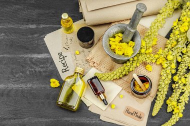 Verbascum çiçekleriyle doğal cilt bakımı, yağlar, kremler ve güzellik tedavileri için bitkisel malzeme. Siyah ahşap arkaplan, üst manzara