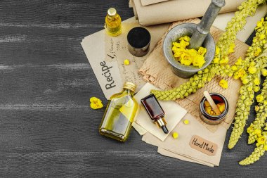 Verbascum çiçekleriyle doğal cilt bakımı, yağlar, kremler ve güzellik tedavileri için bitkisel malzeme. Siyah ahşap arkaplan, üst manzara