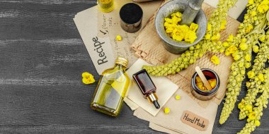 Verbascum çiçekleriyle doğal cilt bakımı, yağlar, kremler ve güzellik tedavileri için bitkisel malzeme. Siyah ahşap arkaplan, pankart biçimi