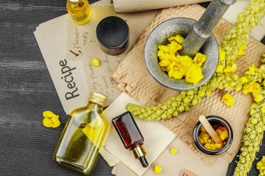 Verbascum çiçekleriyle doğal cilt bakımı, yağlar, kremler ve güzellik tedavileri için bitkisel malzeme. Siyah ahşap arkaplan, üst manzara