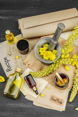 Verbascum çiçekleriyle doğal cilt bakımı, yağlar, kremler ve güzellik tedavileri için bitkisel malzeme. Siyah ahşap arkaplan, üst manzara