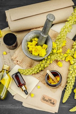 Verbascum çiçekleriyle doğal cilt bakımı, yağlar, kremler ve güzellik tedavileri için bitkisel malzeme. Siyah ahşap arkaplan, üst manzara