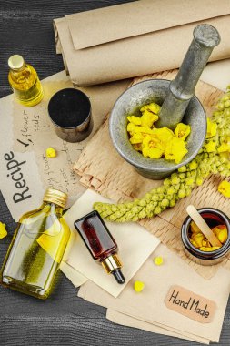 Verbascum çiçekleriyle doğal cilt bakımı, yağlar, kremler ve güzellik tedavileri için bitkisel malzeme. Siyah ahşap arkaplan, üst manzara