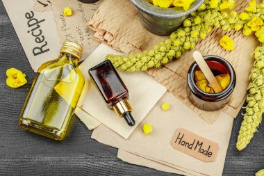 Verbascum çiçekleriyle doğal cilt bakımı, yağlar, kremler ve güzellik tedavileri için bitkisel malzeme. Siyah ahşap arkaplan, üst manzara