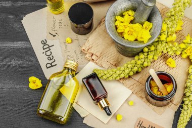 Verbascum çiçekleriyle doğal cilt bakımı, yağlar, kremler ve güzellik tedavileri için bitkisel malzeme. Siyah ahşap arkaplan, üst manzara