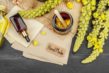 Verbascum çiçekleriyle doğal cilt bakımı, yağlar, kremler ve güzellik tedavileri için bitkisel malzeme. Siyah ahşap arkaplan, üst manzara