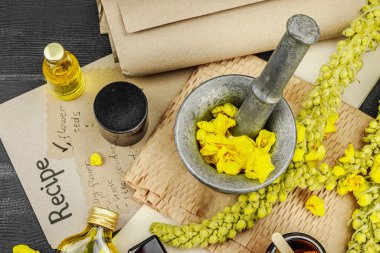 Verbascum çiçekleriyle doğal cilt bakımı, yağlar, kremler ve güzellik tedavileri için bitkisel malzeme. Siyah ahşap arkaplan, üst manzara