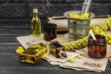 Verbascum çiçekleriyle doğal cilt bakımı, yağlar, kremler ve güzellik tedavileri için bitkisel malzeme. Siyah tahta arkaplan, boşluğu kopyala