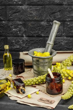 Verbascum çiçekleriyle doğal cilt bakımı, yağlar, kremler ve güzellik tedavileri için bitkisel malzeme. Siyah tahta arkaplan, boşluğu kopyala