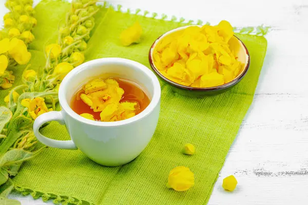 Bir fincan çiçekli ve yapraklı bitki çayı. Doğal ışık, alternatif tıp, klasik şifalı bitki havası, ahşap arka plan, kopyalama alanı