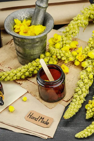 Verbascum çiçekleriyle doğal cilt bakımı, yağlar, kremler ve güzellik tedavileri için bitkisel malzeme. Siyah ahşap arkaplan, kapat