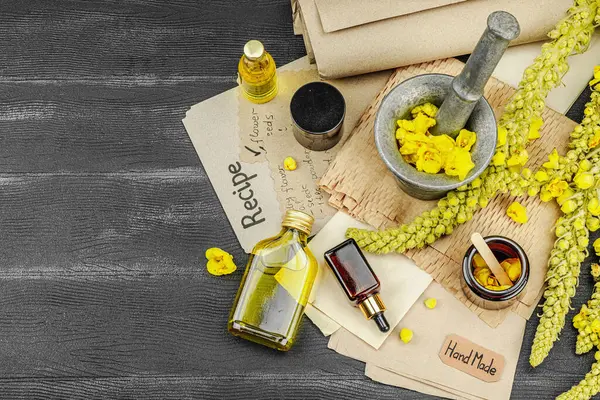 Verbascum çiçekleriyle doğal cilt bakımı, yağlar, kremler ve güzellik tedavileri için bitkisel malzeme. Siyah ahşap arkaplan, üst manzara