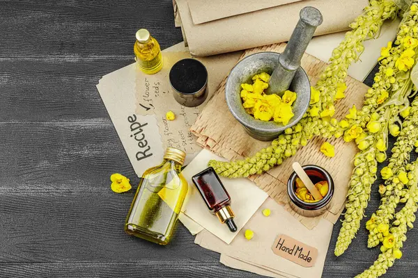 Verbascum çiçekleriyle doğal cilt bakımı, yağlar, kremler ve güzellik tedavileri için bitkisel malzeme. Siyah ahşap arkaplan, üst manzara