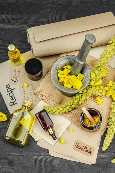 Verbascum çiçekleriyle doğal cilt bakımı, yağlar, kremler ve güzellik tedavileri için bitkisel malzeme. Siyah ahşap arkaplan, üst manzara