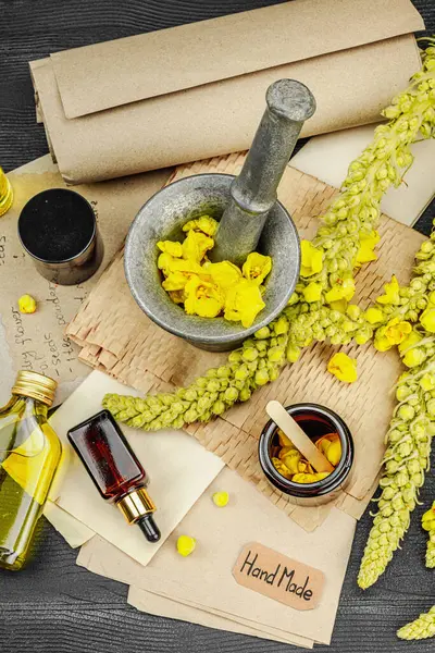 Verbascum çiçekleriyle doğal cilt bakımı, yağlar, kremler ve güzellik tedavileri için bitkisel malzeme. Siyah ahşap arkaplan, üst manzara