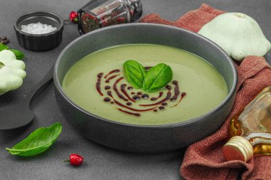Fesleğen ve balzamik jöleli kremalı kabak çorbası taze malzemeler ve baharatlarla moda bir kasede servis ediliyor. Koyu taş beton arka plan, kapat