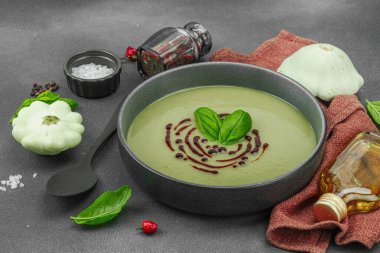 Fesleğen ve balzamik jöleli kremalı kabak çorbası taze malzemeler ve baharatlarla moda bir kasede servis ediliyor. Koyu taş beton arka plan, kapat