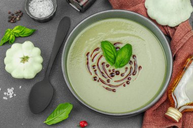 Fesleğen ve balzamik jöleli kremalı kabak çorbası taze malzemeler ve baharatlarla moda bir kasede servis ediliyor. Koyu taş zemin, üst görünüm