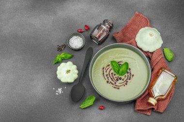 Fesleğen ve balzamik jöleli kremalı kabak çorbası taze malzemeler ve baharatlarla moda bir kasede servis ediliyor. Koyu taş zemin, üst görünüm