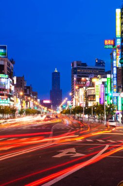 Kaohsiung Tren İstasyonu, Tayvan 'ın önündeki modern kentsel mimari manzara gece araba ışıklarının hareket halindeki rayları ve uzaktaki 85 Sky Tower.