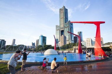 Turistler Kaohsiung, Tayvan 'daki Singuang Ferry Wharf' taki kırmızı çeşmede oynuyorlar. Kaohsiung Limanı 'nın 22. rıhtımının yakınlarında..