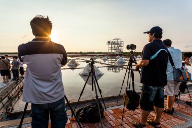 Birçok fotoğrafçı Tainan, Tayvan 'daki Jingzaijiao Tile-Paved Salt Fields' da gün batımı manzarası çekiyor..