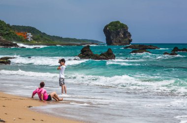 Pingtung, Tayvan 'daki Kenting Ulusal Parkı' ndaki Chuanfanshi Sahili yakınlarındaki plajda oynayan turistler