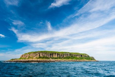 Penghu, Tayvan 'da mavi gökyüzü arka planlı Tongpan Adası' nın güzel manzarası. Ada bazalt mesa karasadır ve bazalt sütunlardan oluşan kayalıklardan oluşan bir kıyı şerididir..