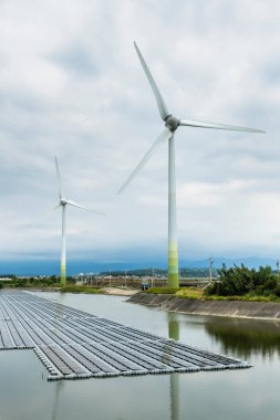 View of the floating solar power system on the Flood Detention Pond with the wind power systems in Miaoli, Taiwan.