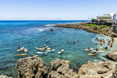 Pingtung, Tayvan- 22 Temmuz 2022: Pingtung, Tayvan 'daki Wanlitong Kenting Ulusal Parkı' nda spor egzersizleri yapan stand-up raketleriyle oynayan turistler.