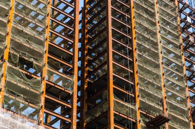 Low-angle view of steel structures of building construction with a blue sky background.