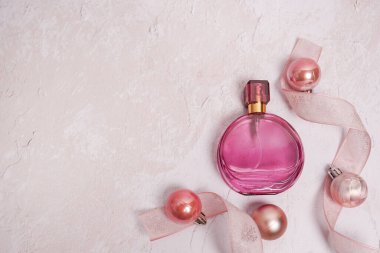 Açık beton zemin üzerine yeni yıl süslemesi yapılmış Noel pembesi parfümü şişesi