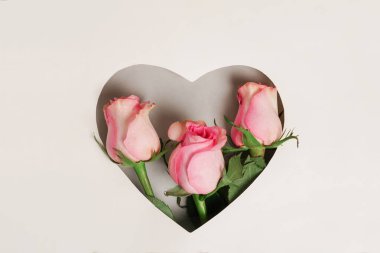 Greeting card with pink roses in heart shape. Anniversary concept.Flat lay