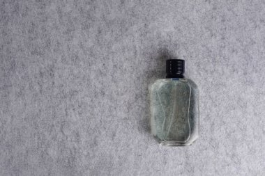 Men perfume bottle on gray textile background, copy space