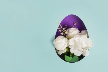 Easter egg with white flowers, blue paper background, copy space
