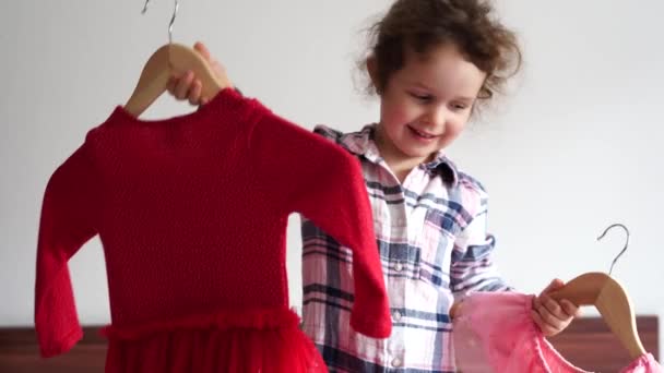 Niña Feliz Elige Entre Vestido Rojo Rosa Permaneciendo Cama Casa — Vídeos de Stock