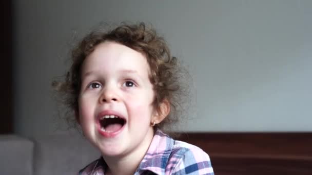 笑いの中の幸せな小さな子供の女の子のバーストのクローズアップ肖像画 子供は家の中で笑う カメラを探す — ストック動画