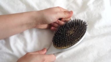 Kadının elleri saç fırçasını temizliyor. Bir sürü düşmüş saç var. Saç dökülme sorunu, hormonal bozukluk, stres, diyet