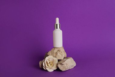 Kozmetik yağlı cam damlatıcı şişesi, zaruri ya da serumun mor arka planda kuru çiçekle taş tezgahta durması. Bitkisel homeopatik ürünler Doğal organik kaplıca ürünleri