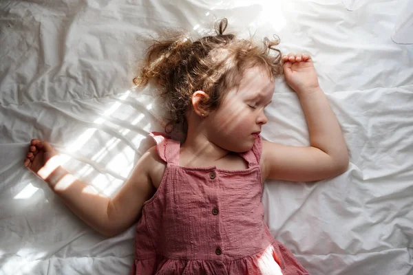 stock image Cute little girl sleeping on bed with sunlights at home