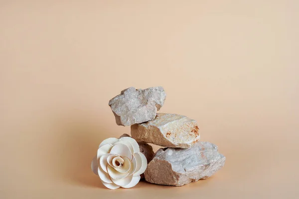 Background for cosmetic products of natural colors. Stone podium with white paper flower on beige table
