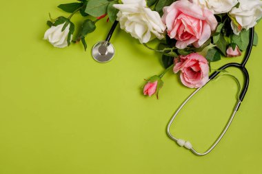 Yeşil arka planda gül çiçekleri ve steteskop. Ulusal Doktor Günü. Hemşire günün kutlu olsun, fotokopi alanı olan tebrik kartı.