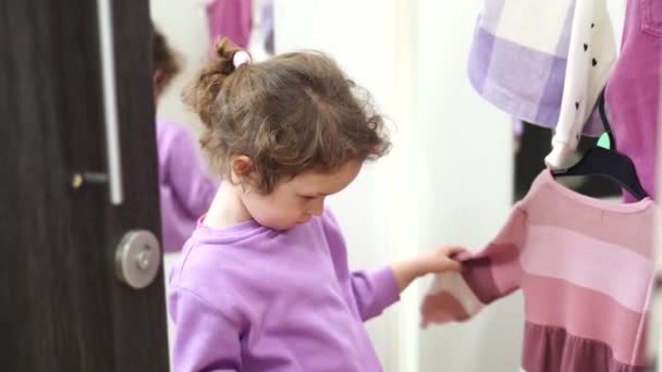 かわいい子供の女の子は店のドレッシングルームでドレスを選択 — ストック動画
