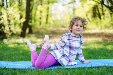 Çocuk kız parkta yoga egzersizi yapıyor, sağlıklı bir yaşam tarzı.