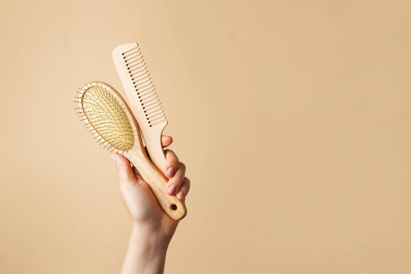 Женщина с двумя деревянными расческами на бежевом фоне, уход за волосами, пространство для копирования