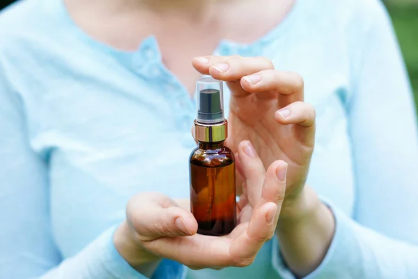 Stock image Woman in blue cloth holding brown glass bottle with spa cosmetic oil. salon therapy, natural eco body care products