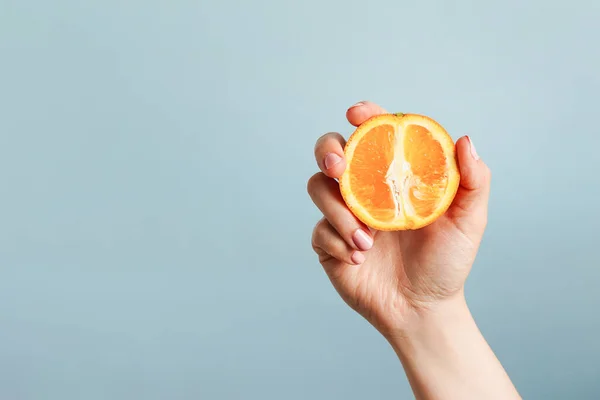 stock image Female hand holding orange on blue background, copy space