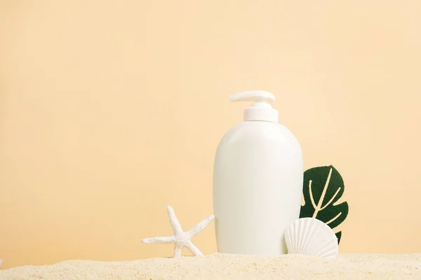 Stock image Summer Skin Care Cosmetic white bottle with shells and monstera leaf on the sand, beige background. sea natural cream package mockup