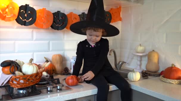 Aranyos Kislány Boszorkányjelmezben Sütőtököt Dekorál Konyhában Halloween Előkészületek — Stock videók